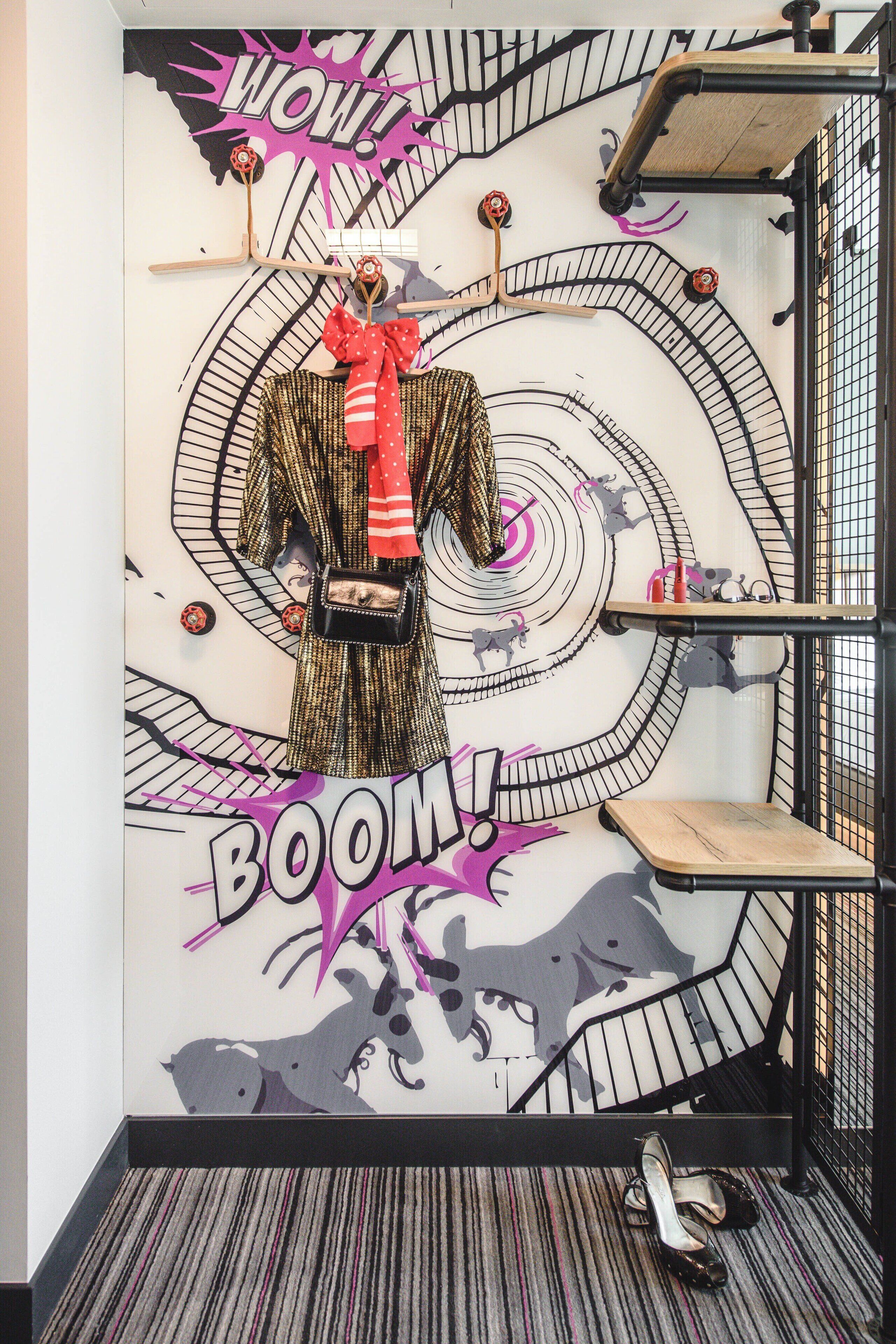 A wall with a spiral design and the words "BOOM!" and "WOW!" in a room with a striped carpet and a metal railing.
