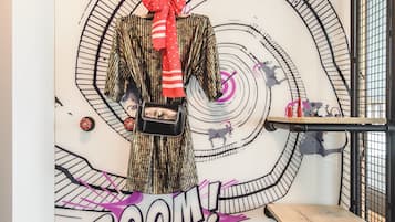 A wall with a spiral design and the words "BOOM!" and "WOW!" in a room with a striped carpet and a metal railing.
