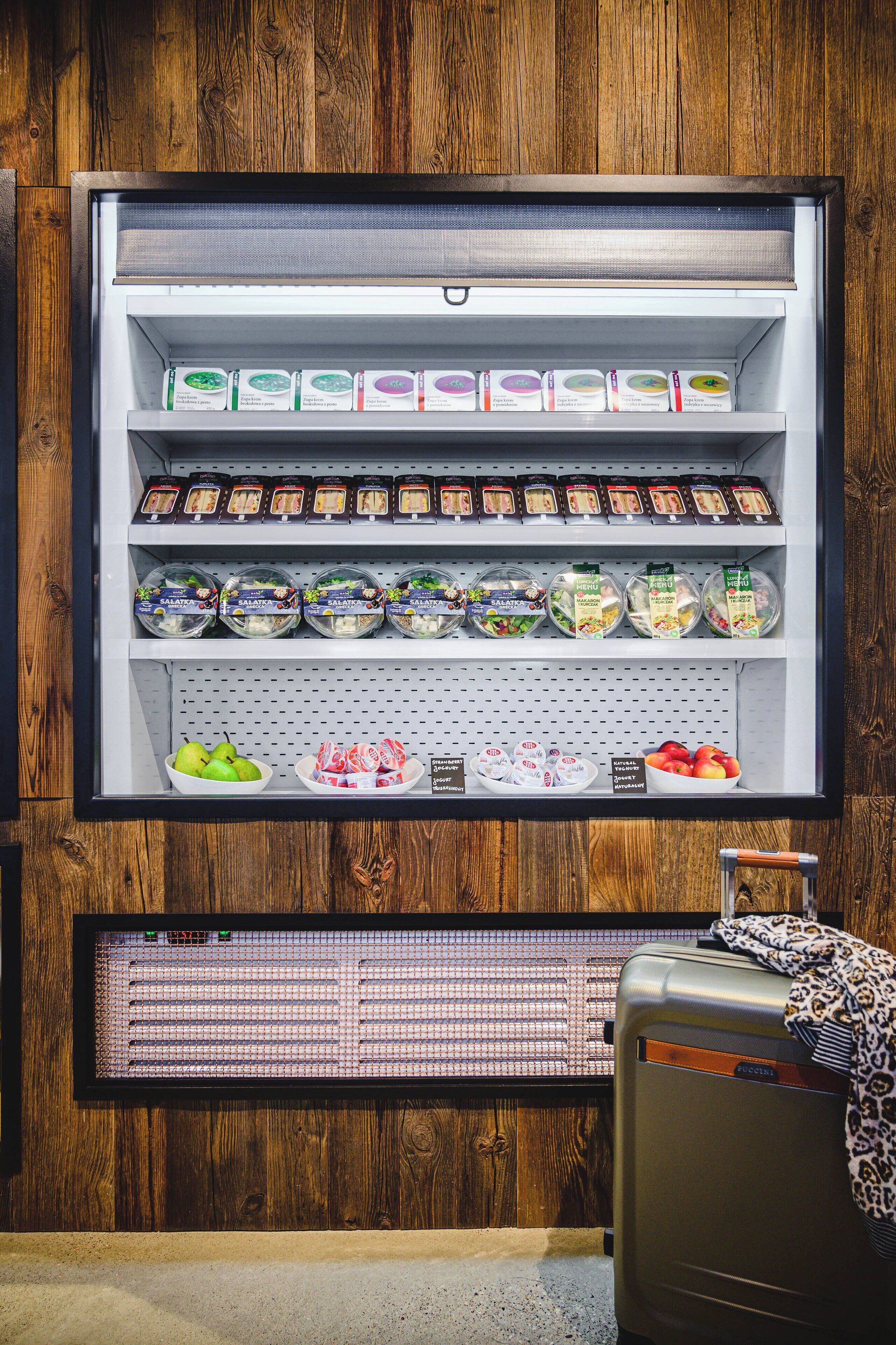 A refrigerated display case with various food items and a suitcase in front.