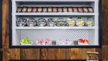 Un mostrador refrigerado con diversos alimentos y una maleta al frente.