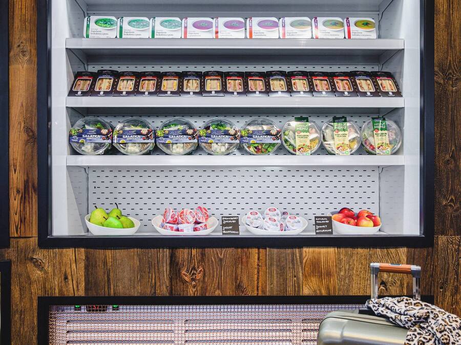 Une vitrine réfrigérée contenant divers produits alimentaires, avec une valise placée devant.