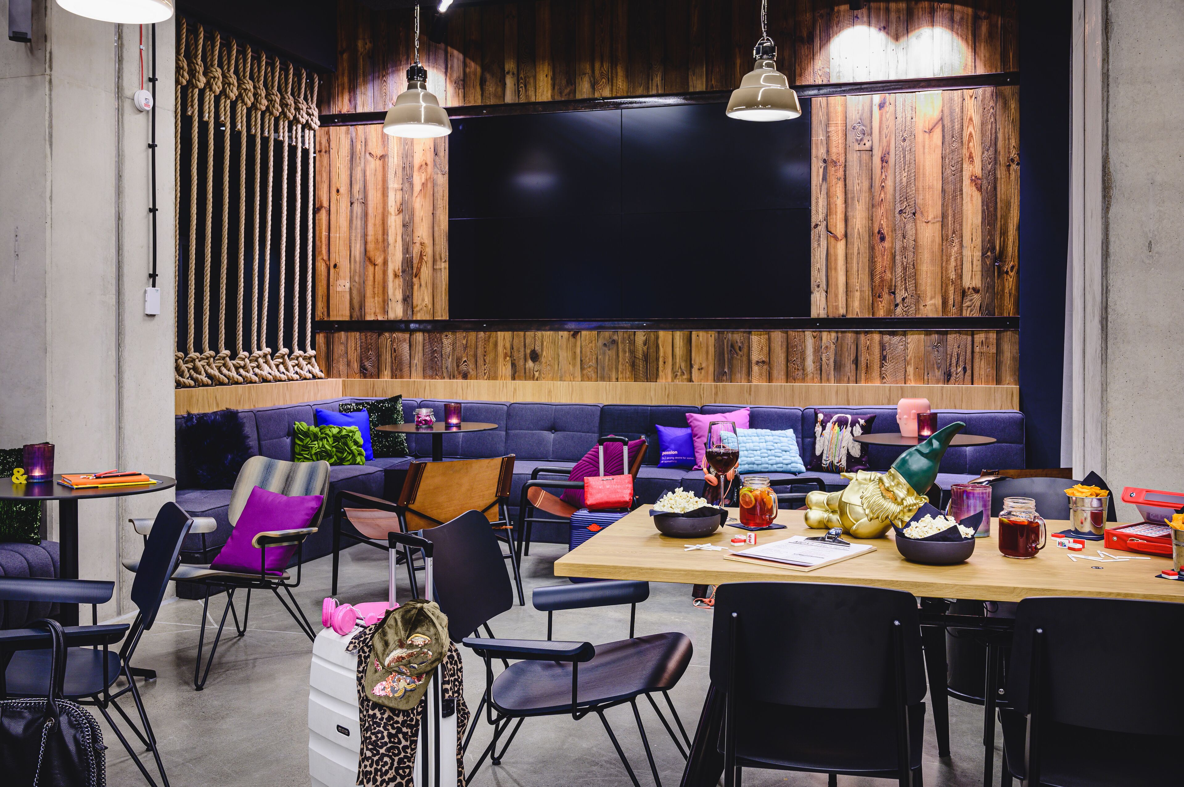 Un comedor moderno con pared de madera, sillas negras y una mesa de madera con comida y bebidas.