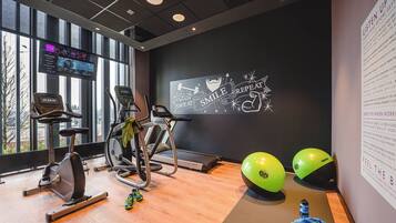 Un gimnasio con equipo cardiovascular, una pared con texto motivacional y un ventanal con vistas.