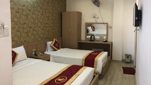 Hotellihuone, jossa on kaksi sänkyä, vaatekaappi, peilillä varustettu työpöytä, tuuletin ja televisio.