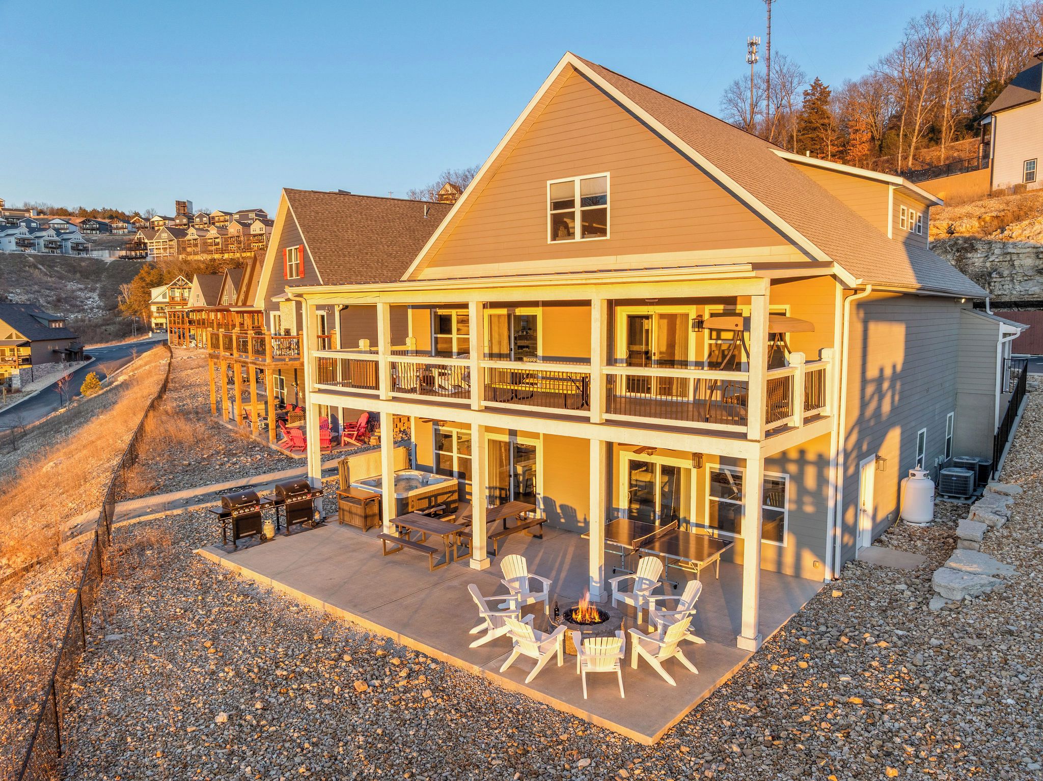 A two-story house with a patio area featuring outdoor furniture and a fire pit.