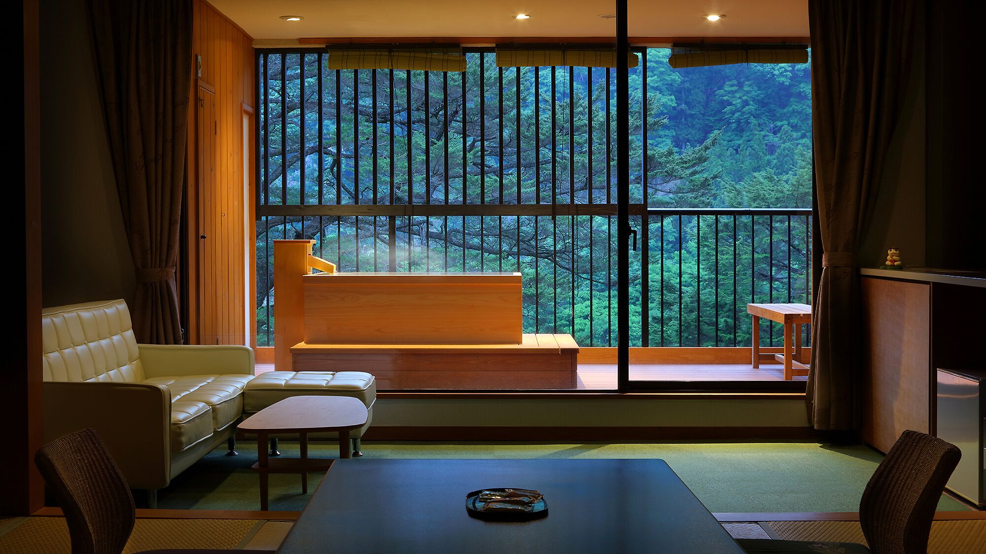 A room with a large window, a sofa, a table, and a small bench.