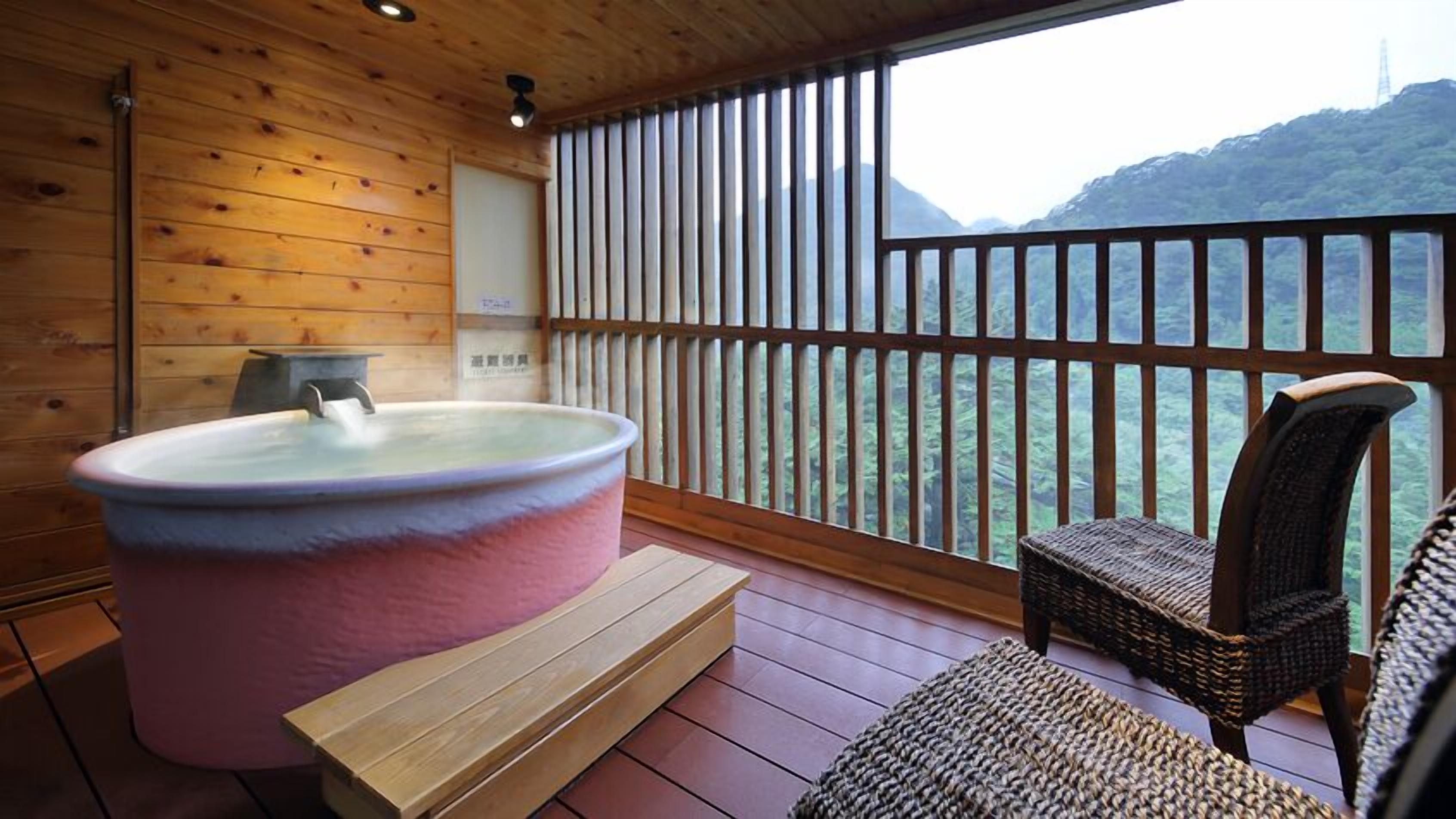 Una habitación de madera con un jacuzzi, una silla y vistas a la montaña.