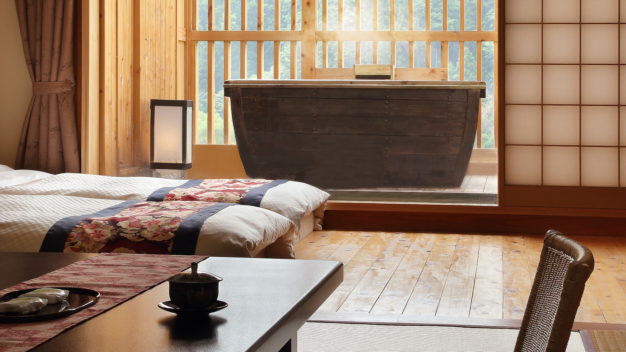 Una habitación con una cama, una mesa con tetera y vistas por una ventana.
