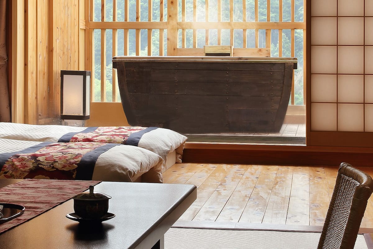Quarto com cama, uma mesa com chaleira e vista pela janela.