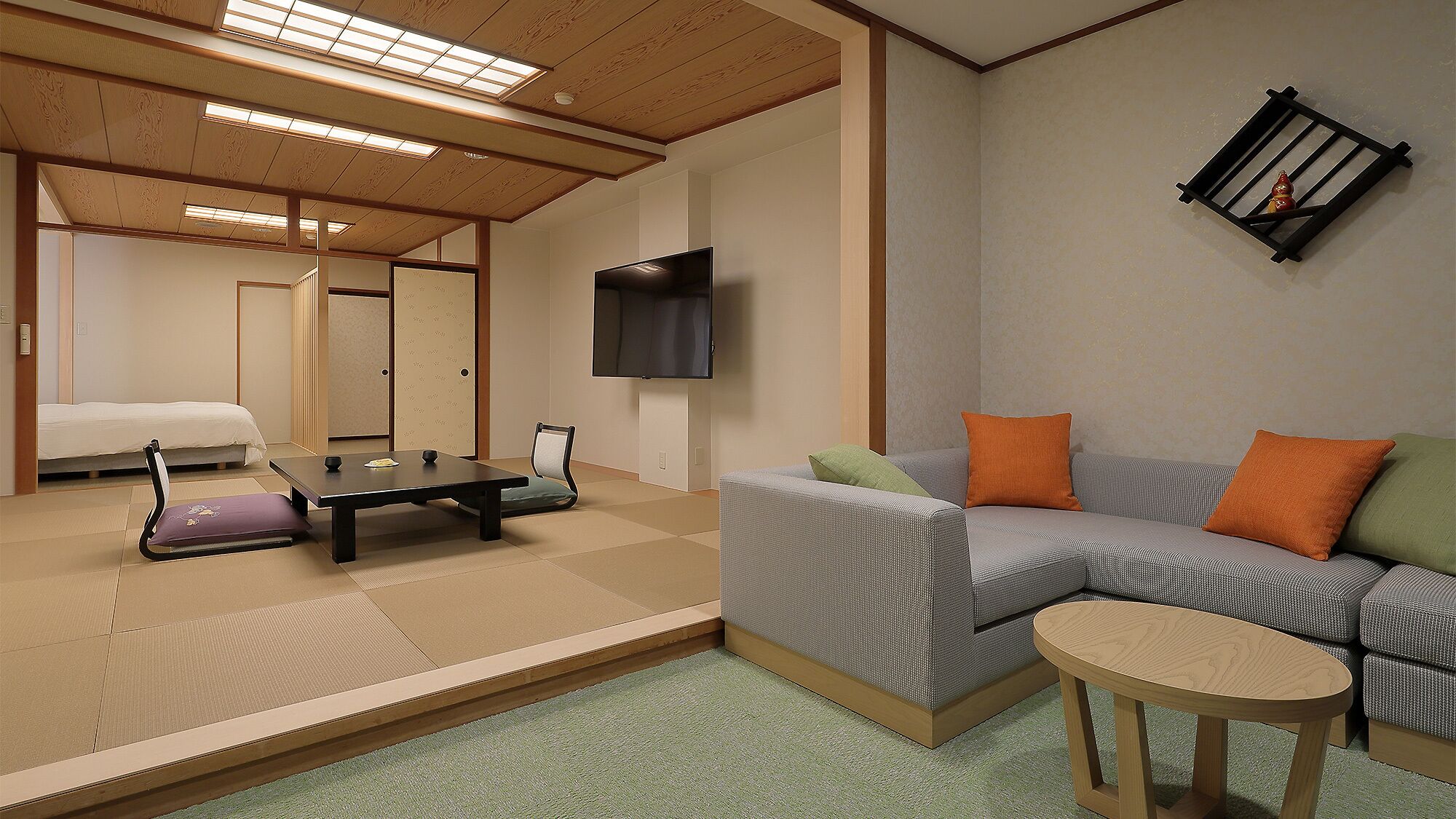 A room with tatami flooring, a low table, a sofa, a television, and a sliding door.