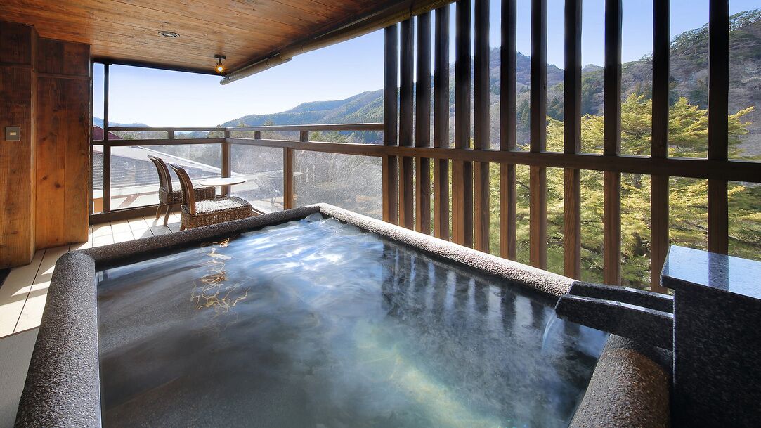 Baño de aguas termales con techo de madera y vistas a montañas.