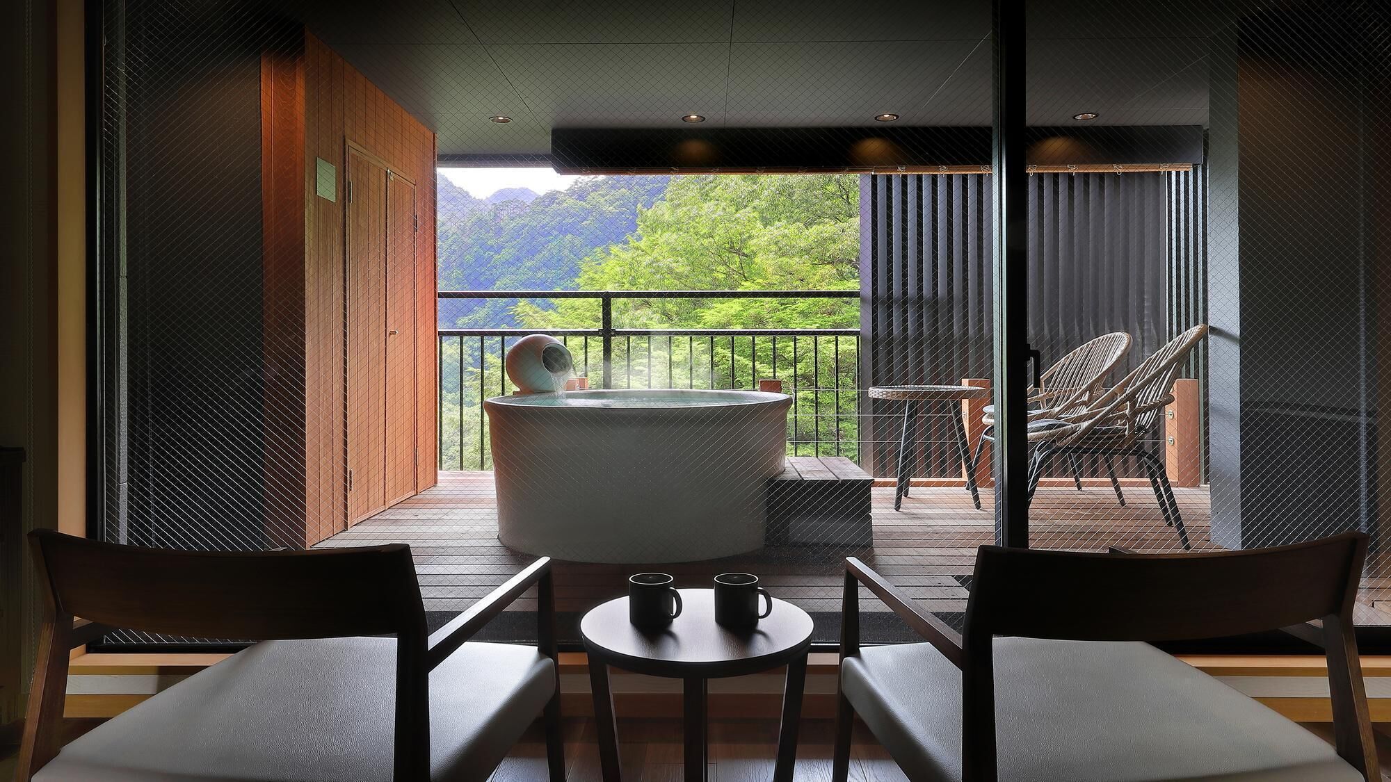 Habitación con bañera de hidromasaje, dos sillones, una mesa y vistas a zonas verdes.