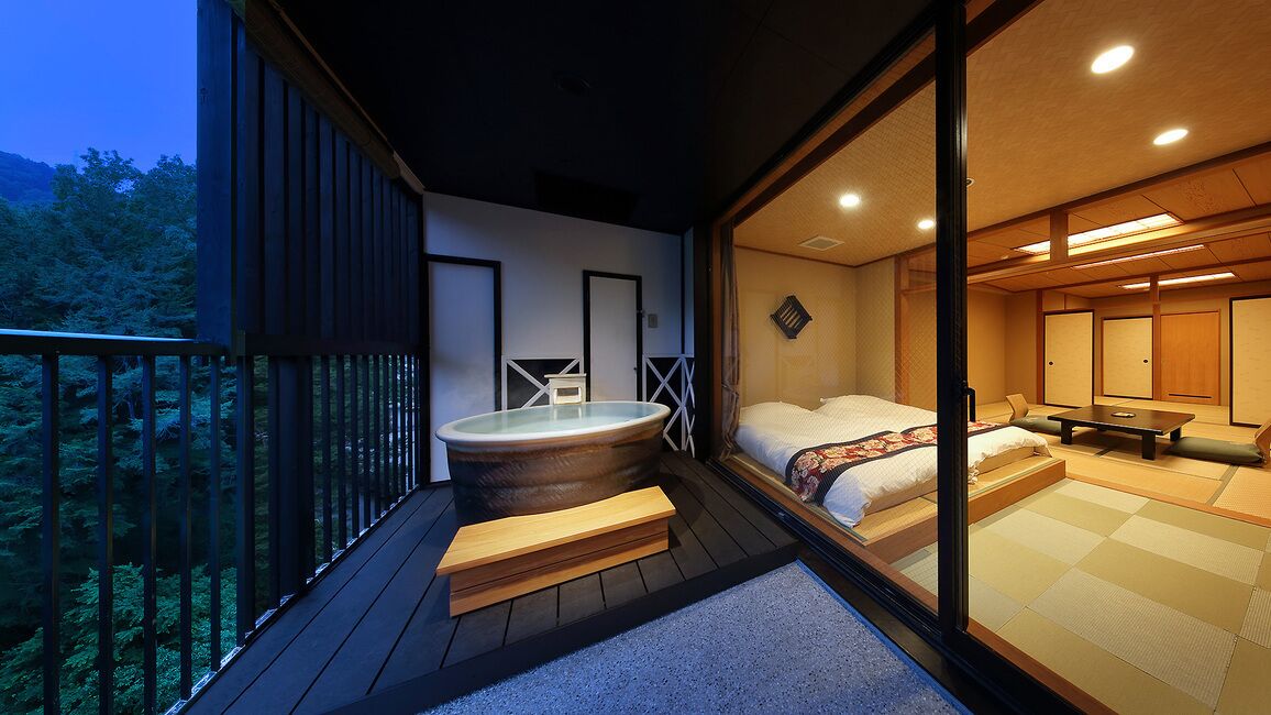 Una habitación tradicional japonesa con suelo de tatami, bañera de hidromasaje y balcón con vistas a una zona boscosa.