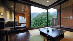 A modern interior with a tatami mat, a low table, and a view of a forested area.