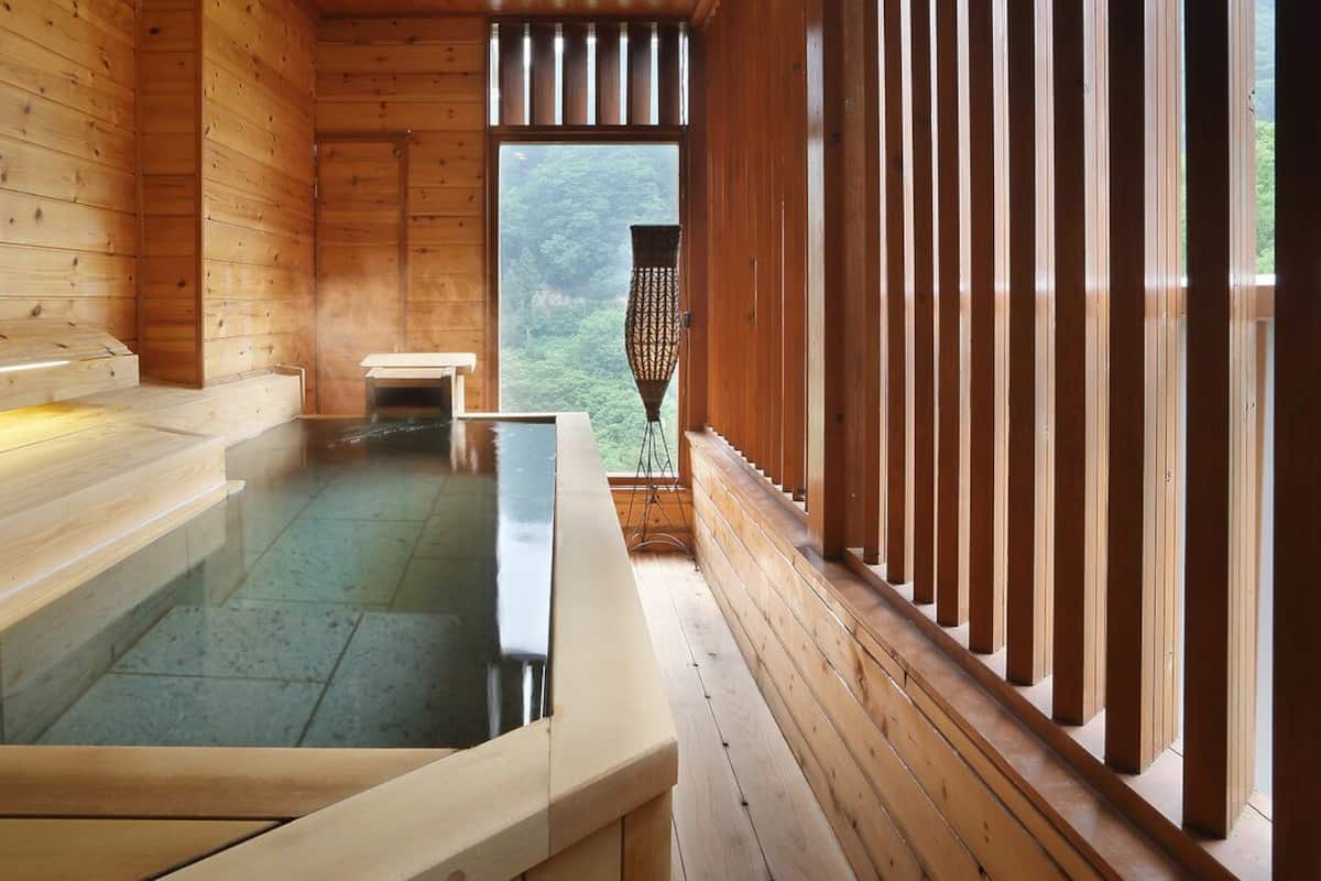 Um spa de madeira com hidromassagem, bancos e vista para a floresta.