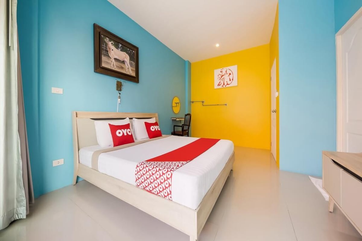 Un dormitorio con cama, mesita de noche, un cuadro enmarcado y una puerta.