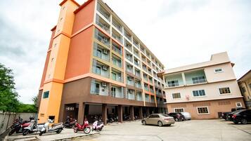A multi-story building with balconies and a parking area.