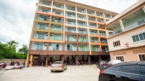 A multi-story building with balconies, air conditioning units, and a parking area with cars and motorcycles. - The Space Huahin (Hua Hin)