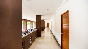 A hallway with a row of wooden doors, a bike rack, and a tiled floor. - The Space Huahin (Hua Hin)