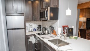 A modern kitchen with stainless steel appliances, a large island with a sink, and wooden cabinets. - 6 Chamonix Lane 1 Bedroom Townhouse by RedAwning (Vail)