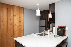 Eine moderne Küche mit Holzausstattung, einer weißen Arbeitsplatte und einem schwarzen Kühlschrank.