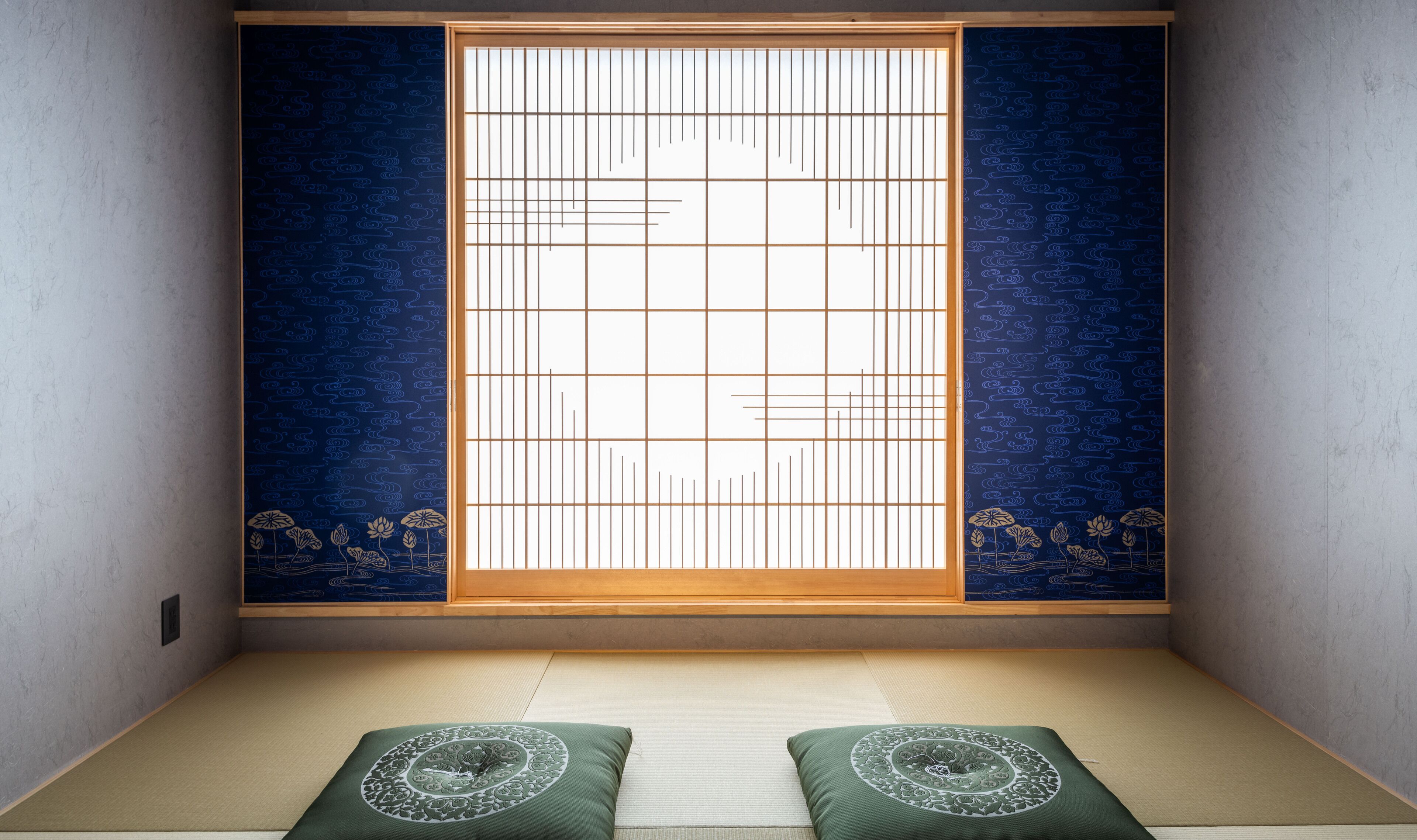 A traditional Japanese room with tatami flooring, a shoji screen, and a futon bed.