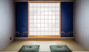 A traditional Japanese room with tatami flooring, a shoji screen, and a futon bed.