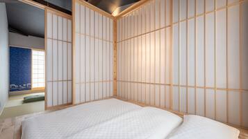 A traditional Japanese-style room with tatami flooring, a low wooden bed frame, and shoji screens.