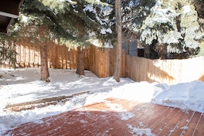 Guests can enjoy a serene backyard with a wooden fence, trees, and a deck.