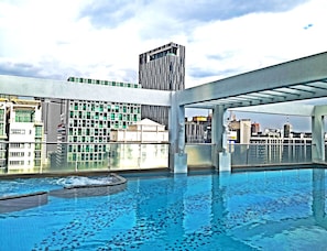 Ein Dachpool mit Blick auf die Stadtlandschaft, darunter moderne Gebäude und ein hoher Wolkenkratzer.
