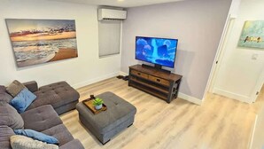 A living room with a sofa set, a coffee table, a flat-screen TV, and artwork on the walls.