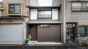 A residential building with a brown door, a small balcony, and a bicycle parked outside. - Tabitabi Stay Shinsen (Kyoto)