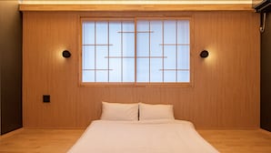 A bedroom with a wooden floor, a bed with white bedding, a shoji screen window, and two wall-mounted lights. - Tabitabi Stay Shinsen (Kyoto)