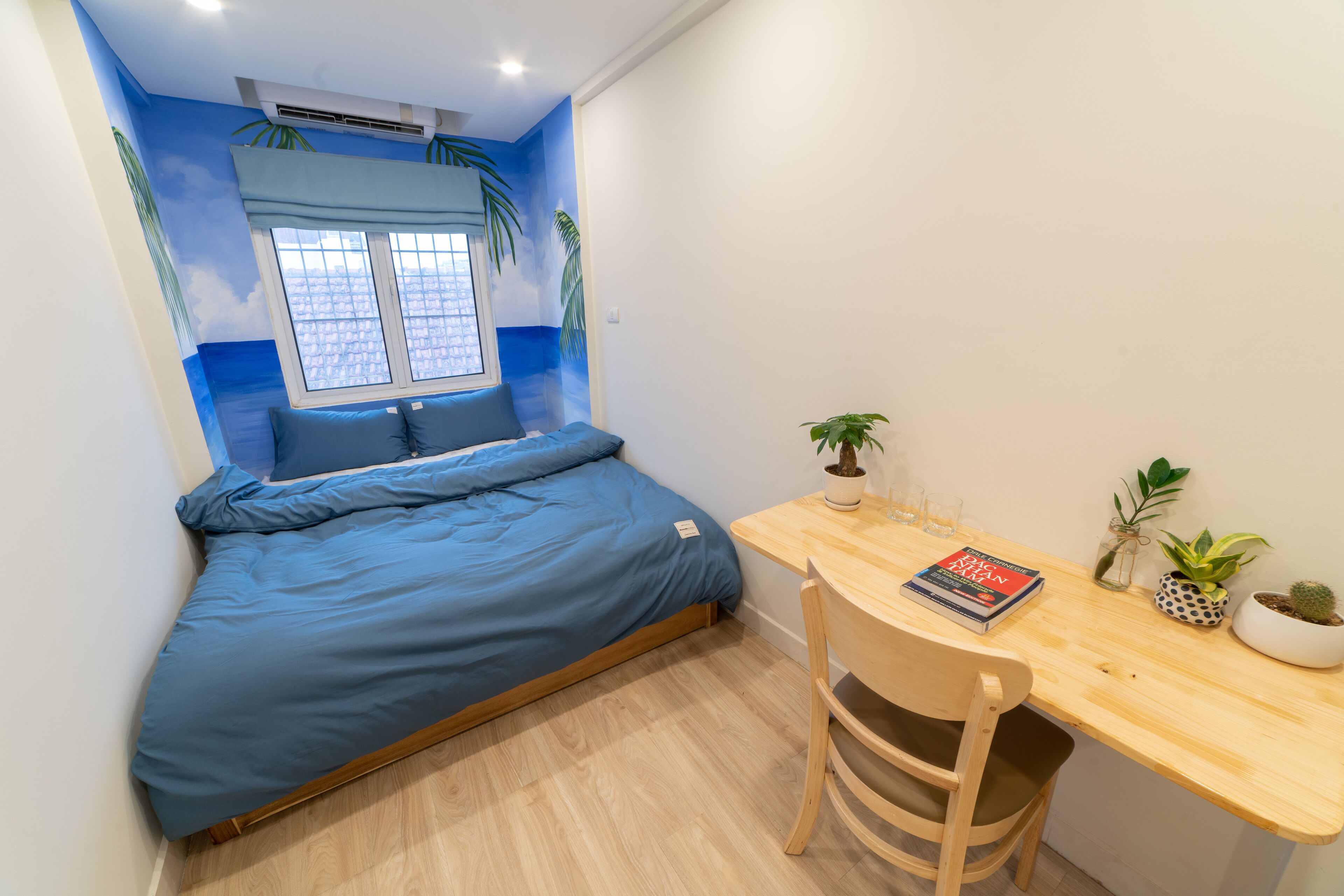 A bedroom with a bed, a desk, and a window.