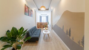Uma sala de estar moderna com um sofá modular, uma mesinha redonda e uma grande planta em vaso.