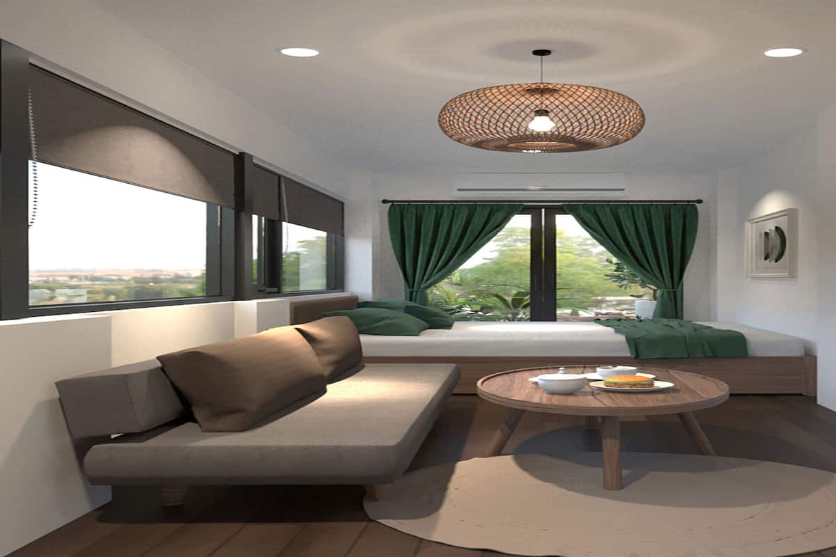 A modern hotel room with a sofa, a round wooden table, a bed with green curtains, a large window, and a TV on a shelf.