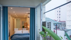 Quarto com uma cama, janela e vista para prédios.