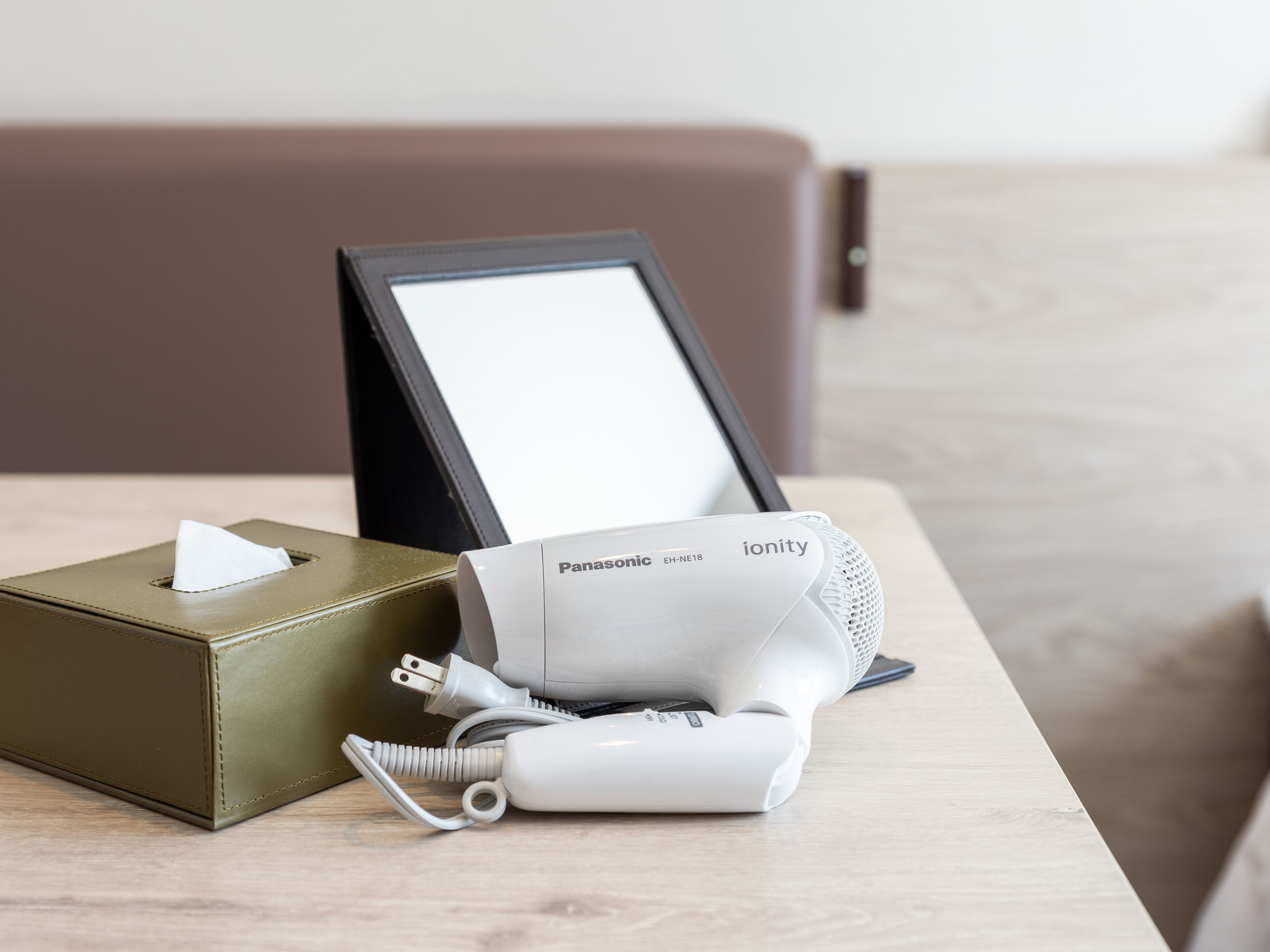 Ein Panasonic ionity Haartrockner auf einem Holztisch zusammen mit einer Papiertuchbox und einem Bilderrahmen.
