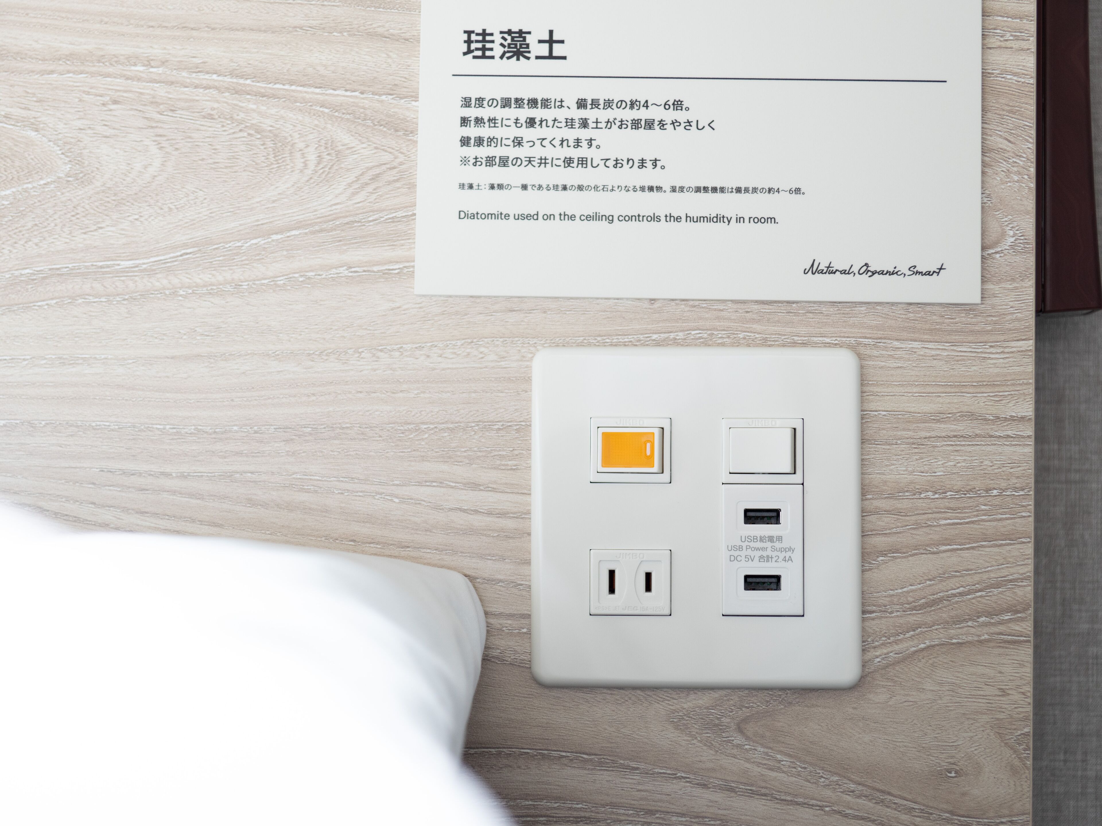 Een wit stopcontact met een USB-poort en een stroomvoorziening op een houten vloer.