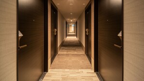 A hallway with wooden walls and carpeted floor, leading to doors numbered 20 and 30. - Superhotel Premier Obihiro ekimae (Obihiro)