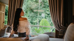 Una habitación con cama, cortinas y vistas al exterior.
