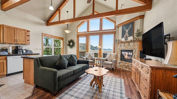 A spacious living area with a sofa, a fireplace, a television, and a stone fireplace surround. - Jackstraw Mountain 32 2 Bedroom Condo by RedAwning (Allenspark)