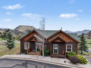Une cabane en rondins dotée de deux entrées séparées, chacune ayant une porte et un petit porche.
