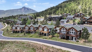 A cluster of log cabin-style lodges with balconies, set against a backdrop of a mountain and forest. - Jackstraw Mountain 32 2 Bedroom Condo by RedAwning (Allenspark)