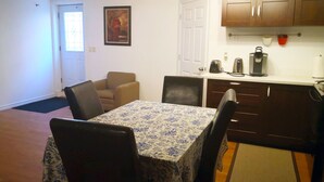 A dining area with a table and chairs, a kitchen with cabinets and appliances, and a door with a window. - GA Stay Oakville Two Bedroom Guest House (Oakville)