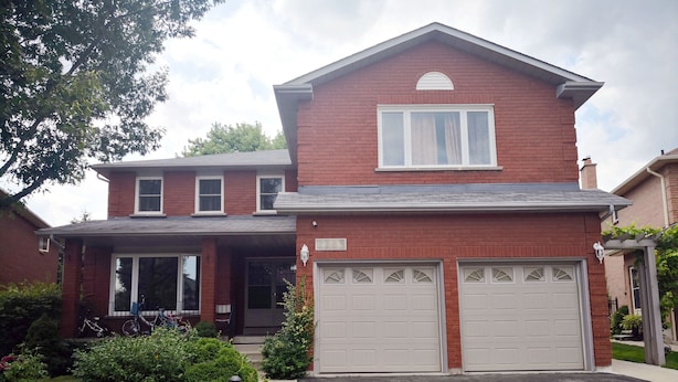A two-story house with a red brick facade, a garage with two white doors, and a small porch area. - GA Stay Oakville Two Bedroom Guest House (Oakville)