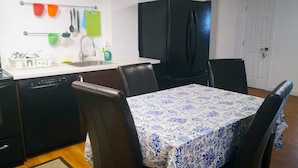 A compact kitchen with a dishwasher, a sink, and a refrigerator. There are chairs around a table with a floral tablecloth. - GA Stay Oakville Two Bedroom Guest House (Oakville)