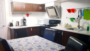 A compact kitchen with a dining table, chairs, a microwave, a coffee maker, and a stove. - GA Stay Oakville Two Bedroom Guest House (Oakville)