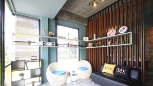 A modern living room with a sofa, two armchairs, a coffee table, and shelves with various items. - The Nichehome - A Lovely Waterside Living (San Sai)