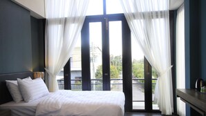 A hotel room with two beds, a desk, and a balcony with curtains. - The Nichehome - A Lovely Waterside Living (San Sai)